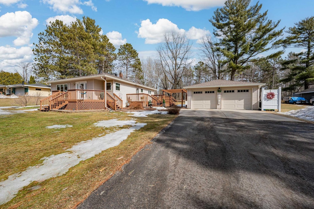 ranch-style home featuring a front lawn, aphalt driveway, an outdoor structure, a wooden deck, and a chimney