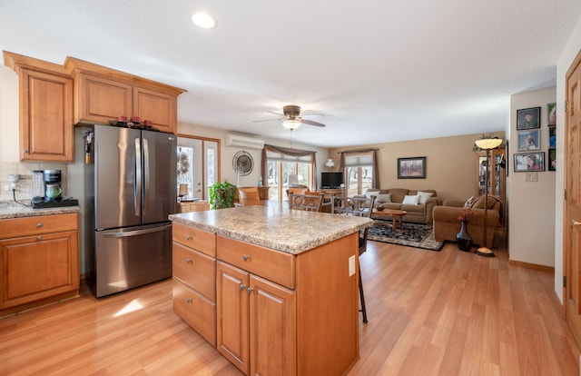 kitchen featuring brown cabinetry, light wood-style flooring, a center island, and freestanding refrigerator