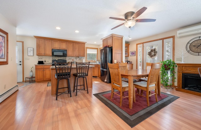 dining space with a fireplace, light wood-style floors, baseboard heating, and a wall mounted AC