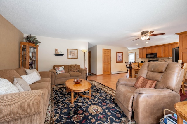 living room featuring light wood-style flooring, ceiling fan, and a baseboard radiator