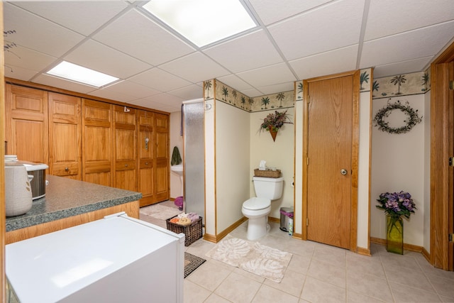 bathroom with tile patterned floors, a drop ceiling, toilet, and baseboards