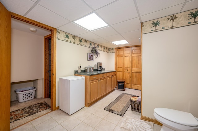 clothes washing area with light tile patterned floors and baseboards