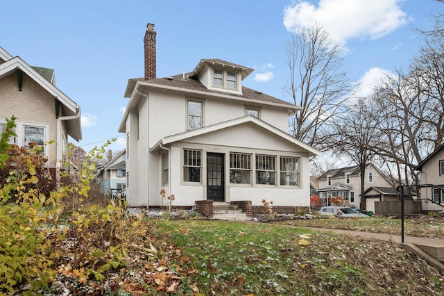 american foursquare style home featuring entry steps, stucco siding, a shingled roof, and a chimney