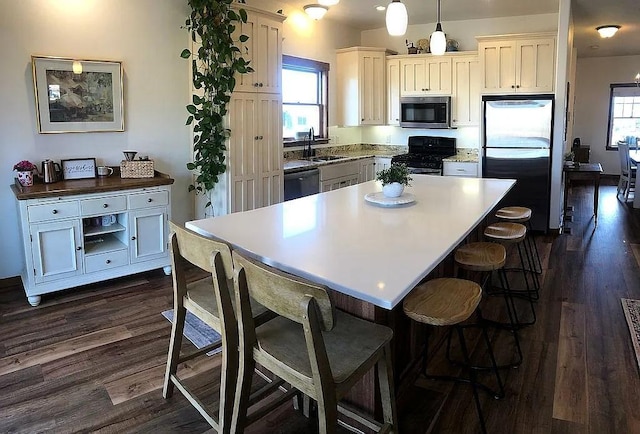 kitchen featuring black gas stove, a healthy amount of sunlight, freestanding refrigerator, and a sink