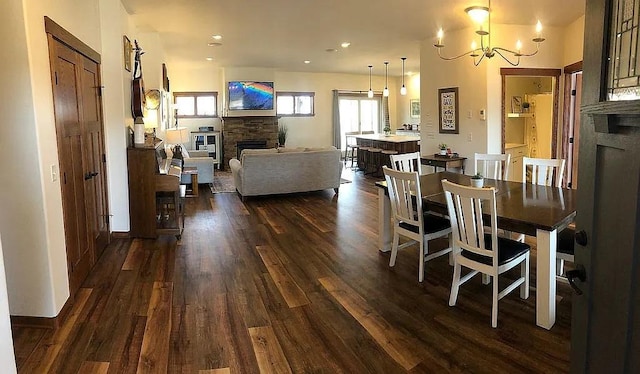 dining area featuring dark wood-style floors, a notable chandelier, and a fireplace