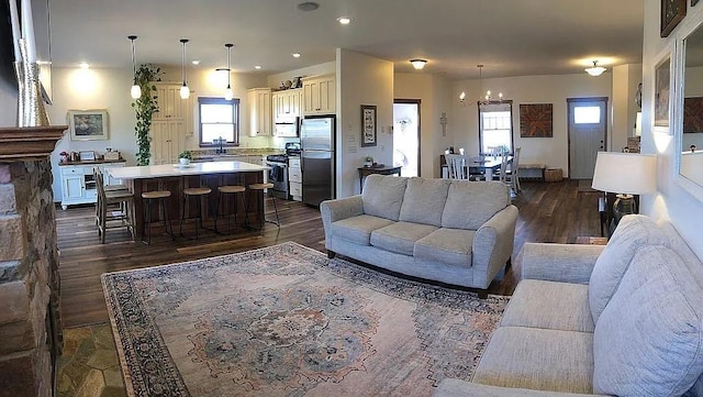 living room with an inviting chandelier, a healthy amount of sunlight, and dark wood-style flooring