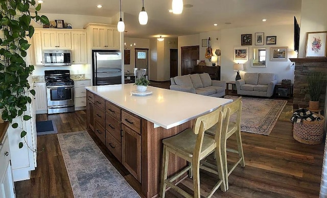 kitchen with dark wood finished floors, light countertops, a center island, and stainless steel appliances