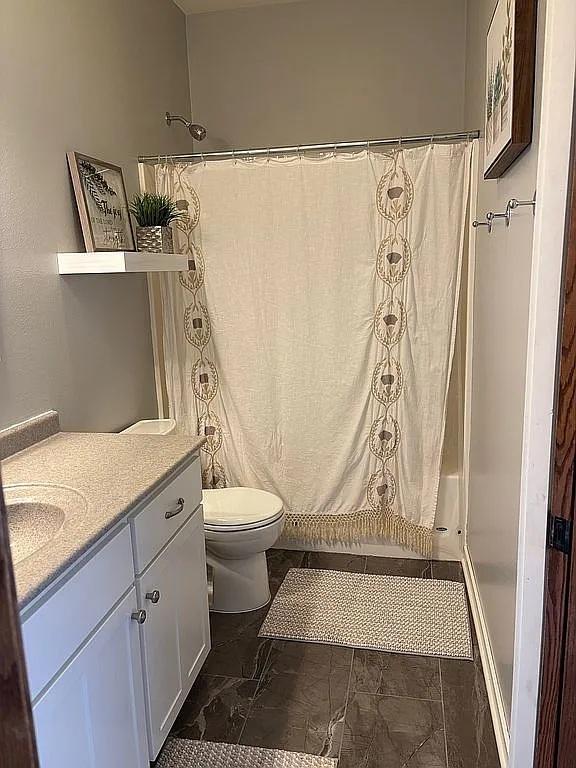 full bathroom featuring a shower with shower curtain, toilet, and vanity