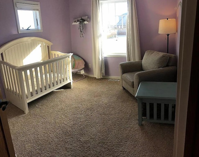 bedroom featuring carpet flooring, multiple windows, a crib, and baseboards