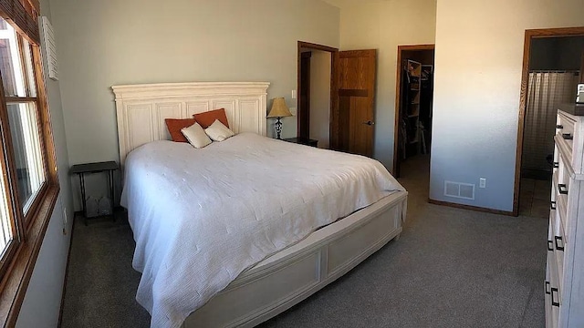 carpeted bedroom with a walk in closet, baseboards, visible vents, and a closet