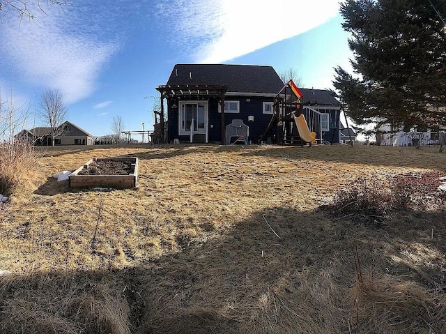 rear view of property with a vegetable garden and a playground