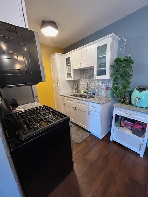 kitchen featuring a sink, backsplash, black gas stove, white cabinetry, and dark wood-style flooring