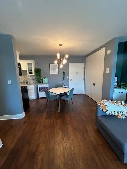 dining space featuring a notable chandelier, baseboards, and dark wood-style flooring