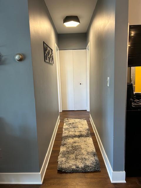 hallway with dark wood-style floors and baseboards