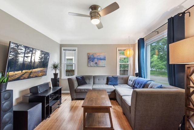 living room featuring light wood-style flooring, baseboards, and ceiling fan