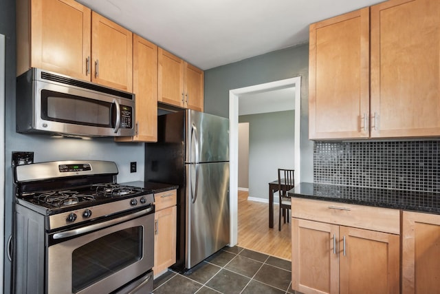 kitchen featuring dark tile patterned floors, backsplash, light brown cabinets, and stainless steel appliances