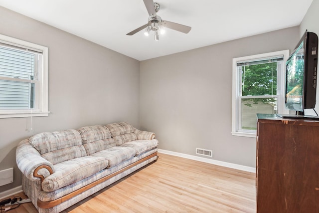 living area with ceiling fan, visible vents, baseboards, and wood finished floors