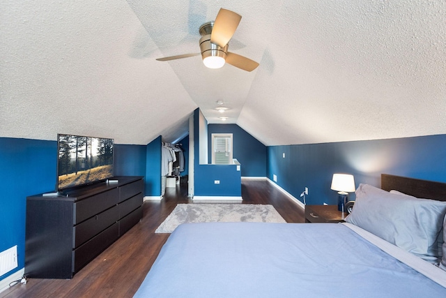 bedroom featuring wood finished floors, baseboards, lofted ceiling, ceiling fan, and a textured ceiling