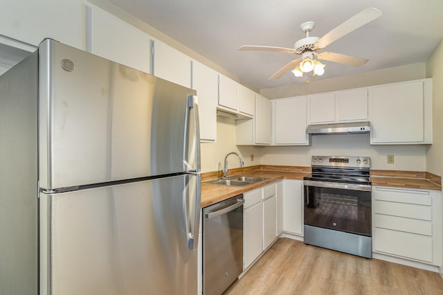 kitchen with light wood finished floors, a sink, stainless steel appliances, under cabinet range hood, and wood counters