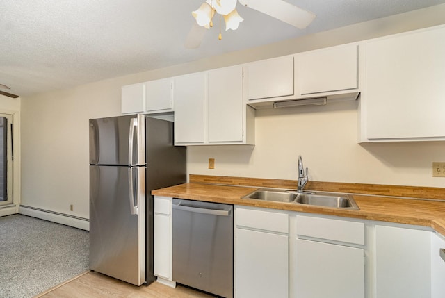 kitchen with a sink, baseboard heating, appliances with stainless steel finishes, and ceiling fan