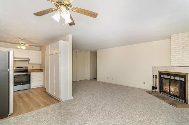 unfurnished living room featuring a fireplace, a ceiling fan, and light carpet