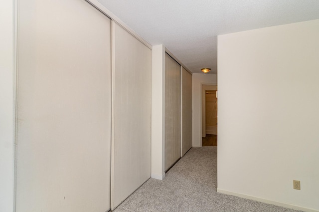 hall featuring baseboards and light carpet