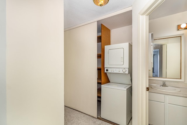 laundry room featuring a sink, a textured ceiling, laundry area, and stacked washer and dryer