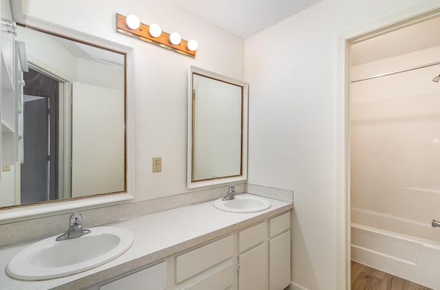 bathroom featuring a sink, shower / washtub combination, wood finished floors, and double vanity