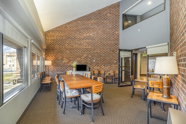 dining room with carpet flooring, brick wall, and high vaulted ceiling