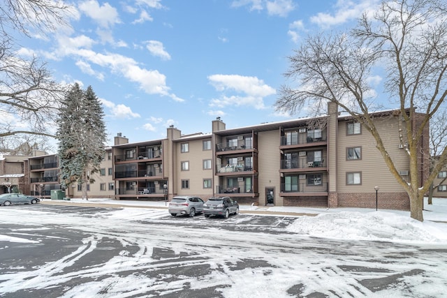 snow covered property with uncovered parking