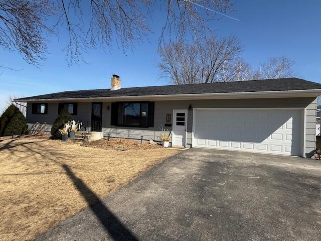 single story home featuring aphalt driveway, a garage, and a chimney