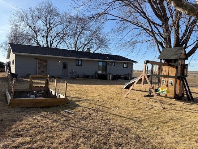 rear view of property featuring a chimney and a playground