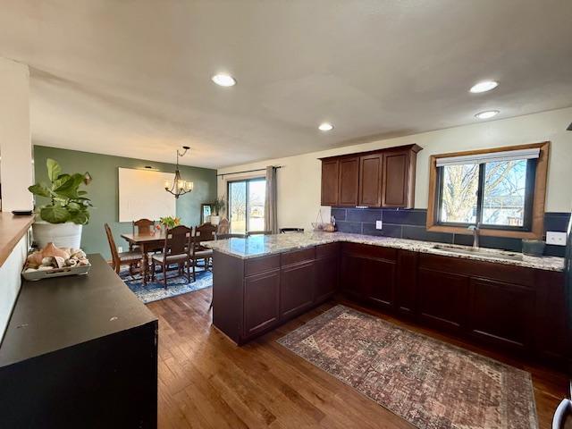 kitchen with tasteful backsplash, dark wood-type flooring, recessed lighting, a peninsula, and a sink