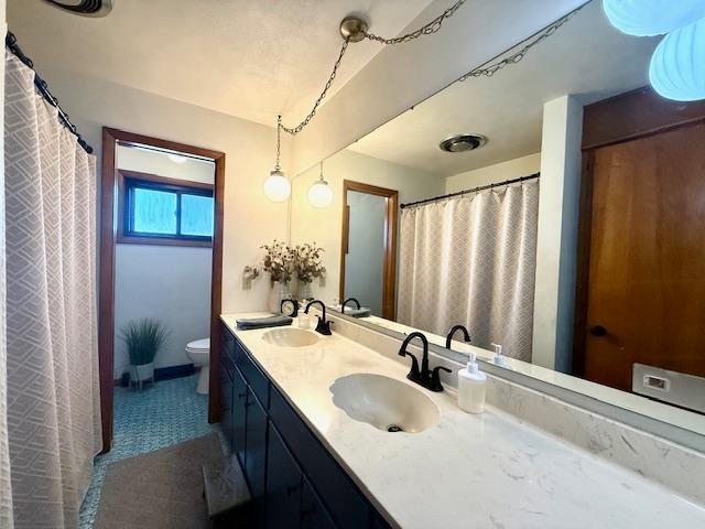 full bath featuring double vanity, toilet, and a sink