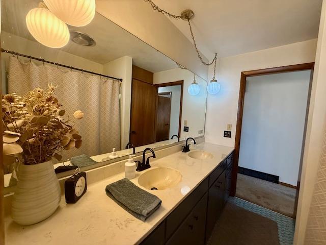 bathroom featuring double vanity, baseboards, and a sink