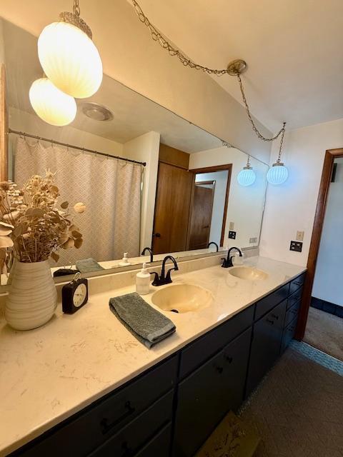 full bathroom featuring a sink, baseboards, and double vanity