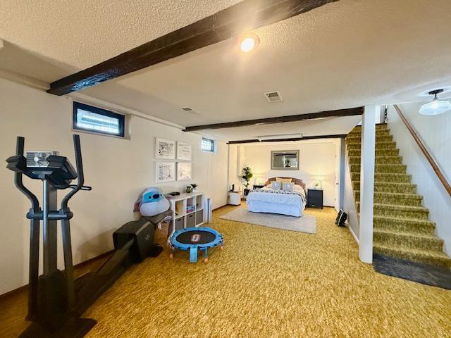 bedroom with beam ceiling, visible vents, a textured ceiling, and carpet floors