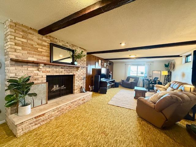 carpeted living room with a brick fireplace, beamed ceiling, and a textured ceiling