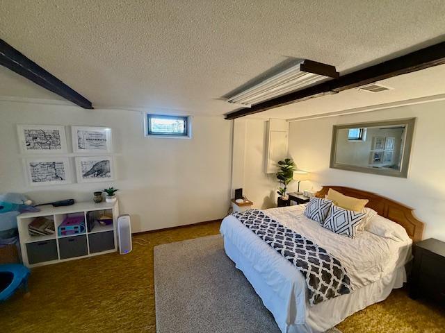 bedroom with beamed ceiling, a textured ceiling, and carpet flooring