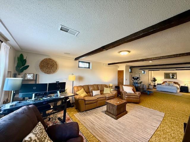 living room with visible vents, beam ceiling, and a textured ceiling