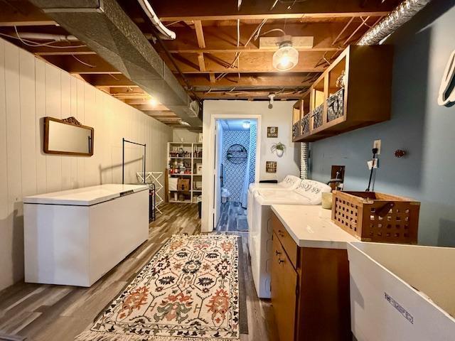 laundry area with wood finished floors, cabinet space, and washing machine and dryer