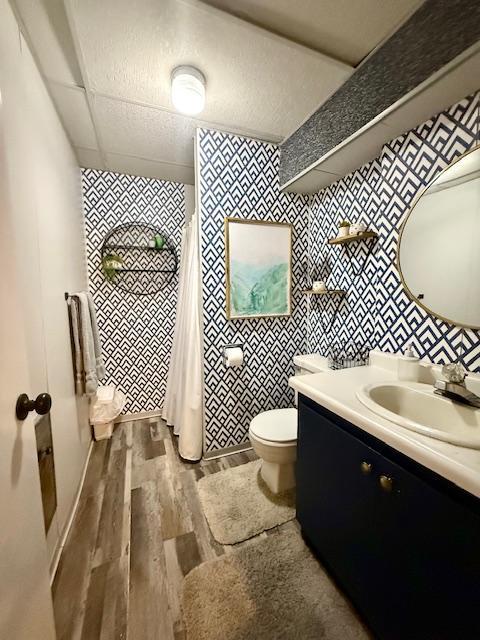 full bath featuring a shower with curtain, toilet, wood finished floors, tile walls, and vanity