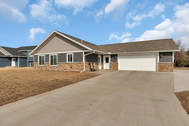 view of front of property with stone siding, an attached garage, and driveway