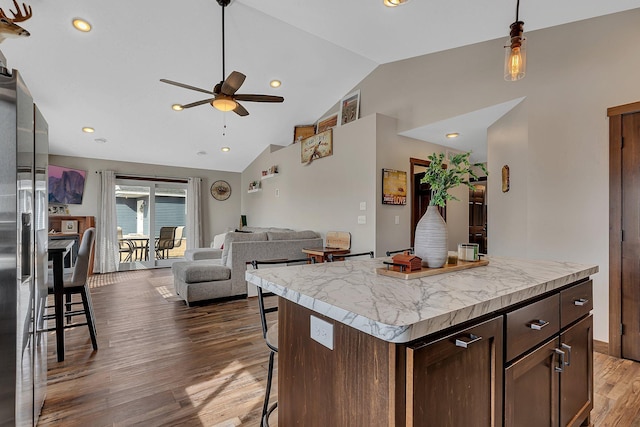 kitchen with dark wood finished floors, light countertops, a breakfast bar area, and open floor plan