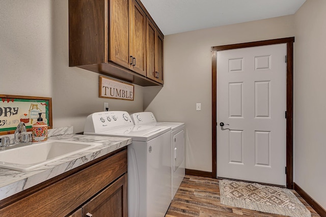 clothes washing area featuring light wood finished floors, baseboards, washer and dryer, cabinet space, and a sink