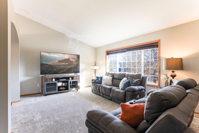 carpeted living area featuring baseboards, arched walkways, and vaulted ceiling