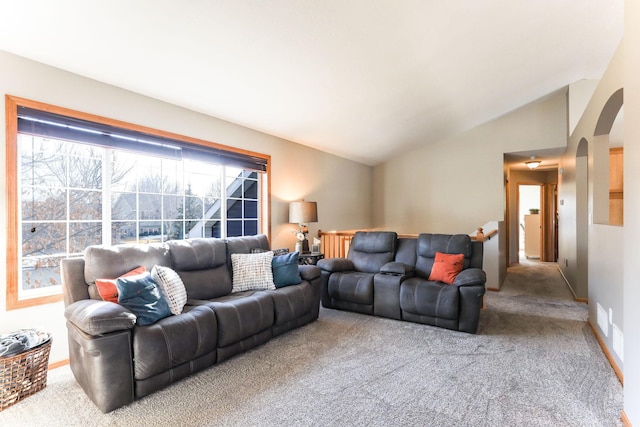 living room featuring lofted ceiling, carpet flooring, baseboards, and arched walkways