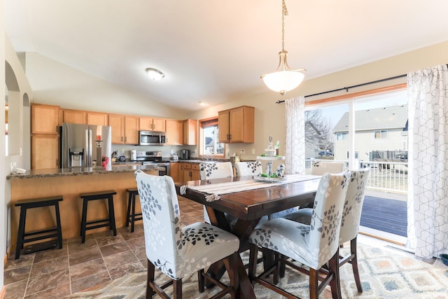 dining area with visible vents, lofted ceiling, arched walkways, and stone finish floor