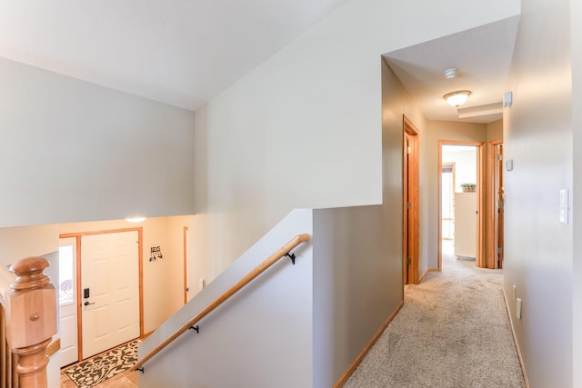 corridor with an upstairs landing, carpet flooring, and baseboards