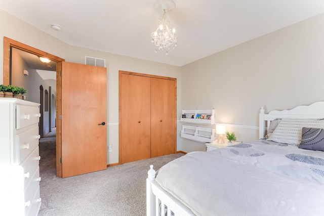 bedroom with a closet, visible vents, a chandelier, and carpet floors